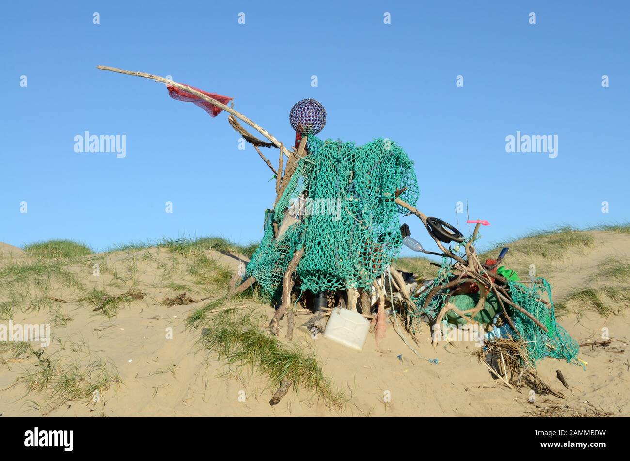 Scultura realizzata da rifiuti in plastica e spazzatura detriti sulla spiaggia pronti per essere raccolti Foto Stock