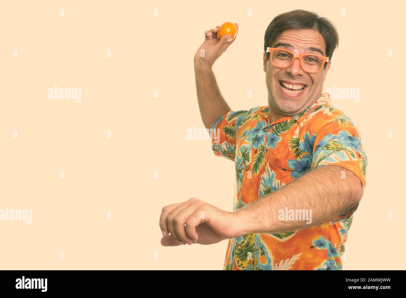 Felice turista persiano uomo sorridente e pronto a gettare arancione mentre indossa occhiali Foto Stock