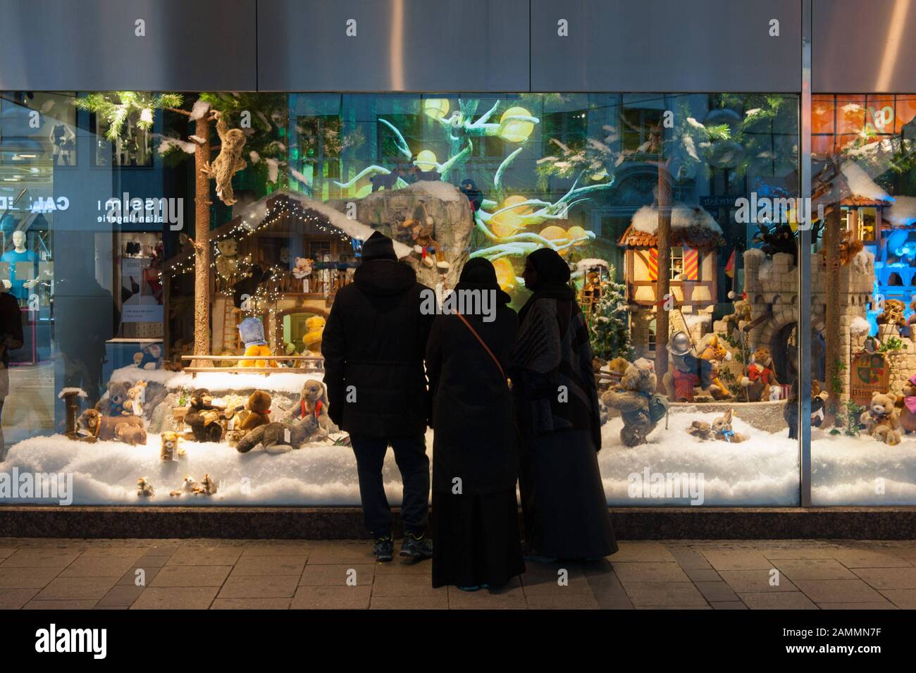 I turisti arabi hanno la vista sulle decorazioni natalizie nella vetrina di Galeria Kaufhof a Marienplatz. [traduzione automatizzata] Foto Stock