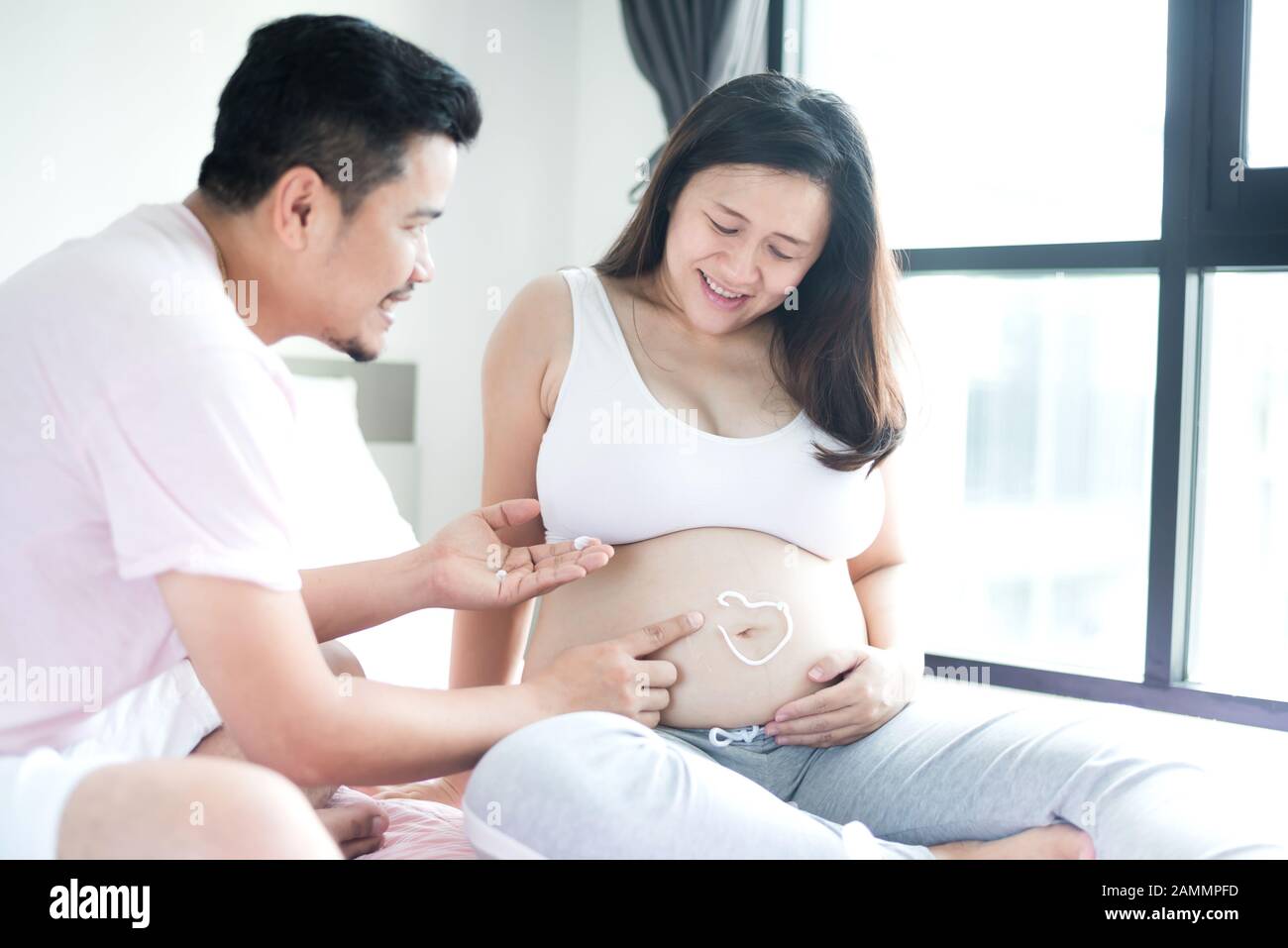 Donna incinta asiatica. Mamma e neonato. Giornata della madre e giornata internazionale delle donne. Relax e svago con marito a casa Foto Stock