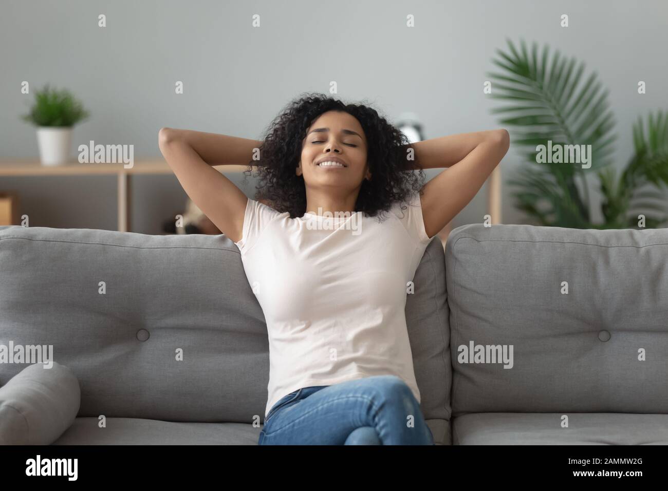 Serena donna africana si appoggiò sul divano a casa Foto Stock