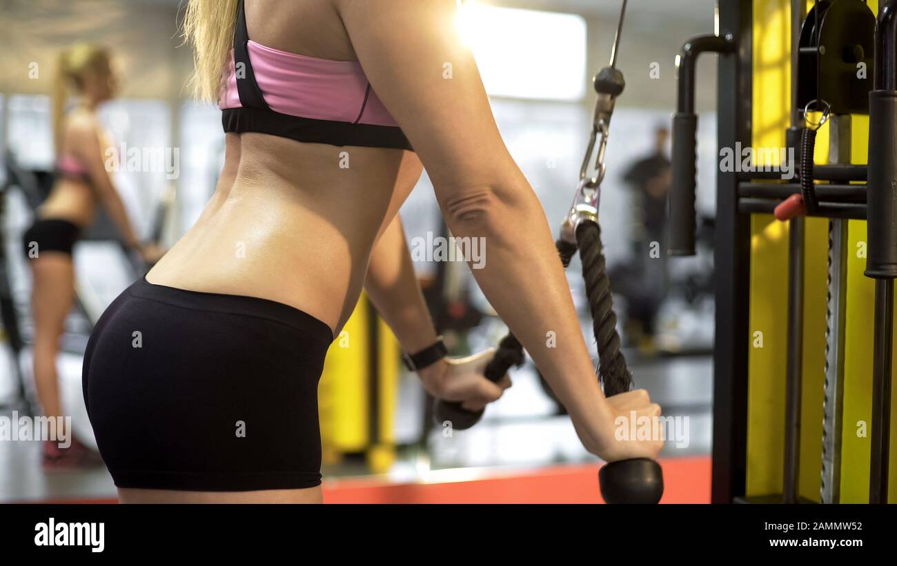 Giovane donna bionda allenarsi in palestra, sport corpo forma, tiro-giù esercizio Foto Stock