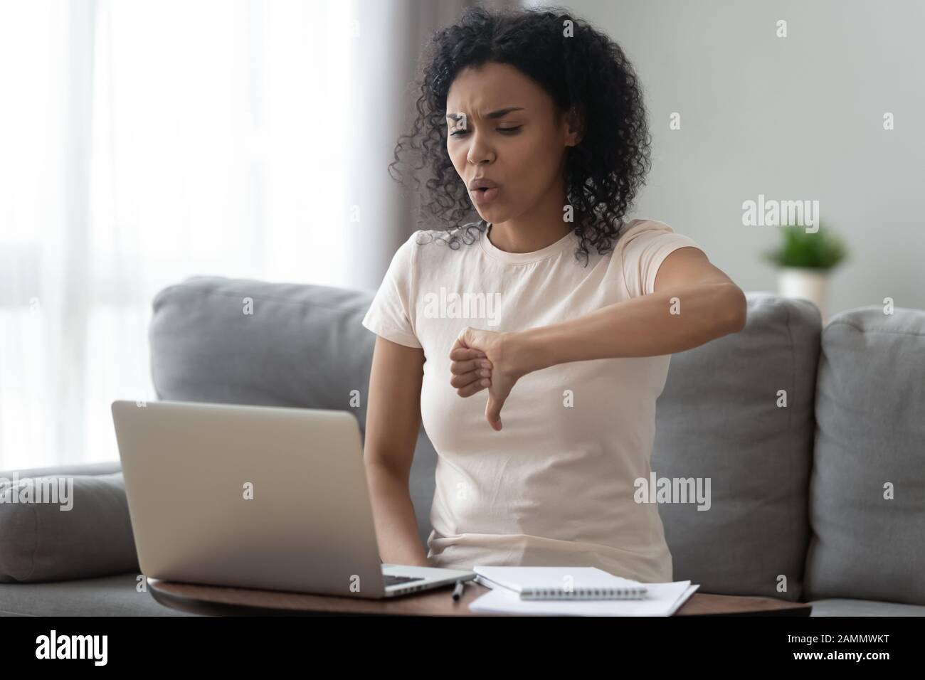 Donna africana insoddisfatta che guarda lo schermo del computer che mostra pollici giù Foto Stock