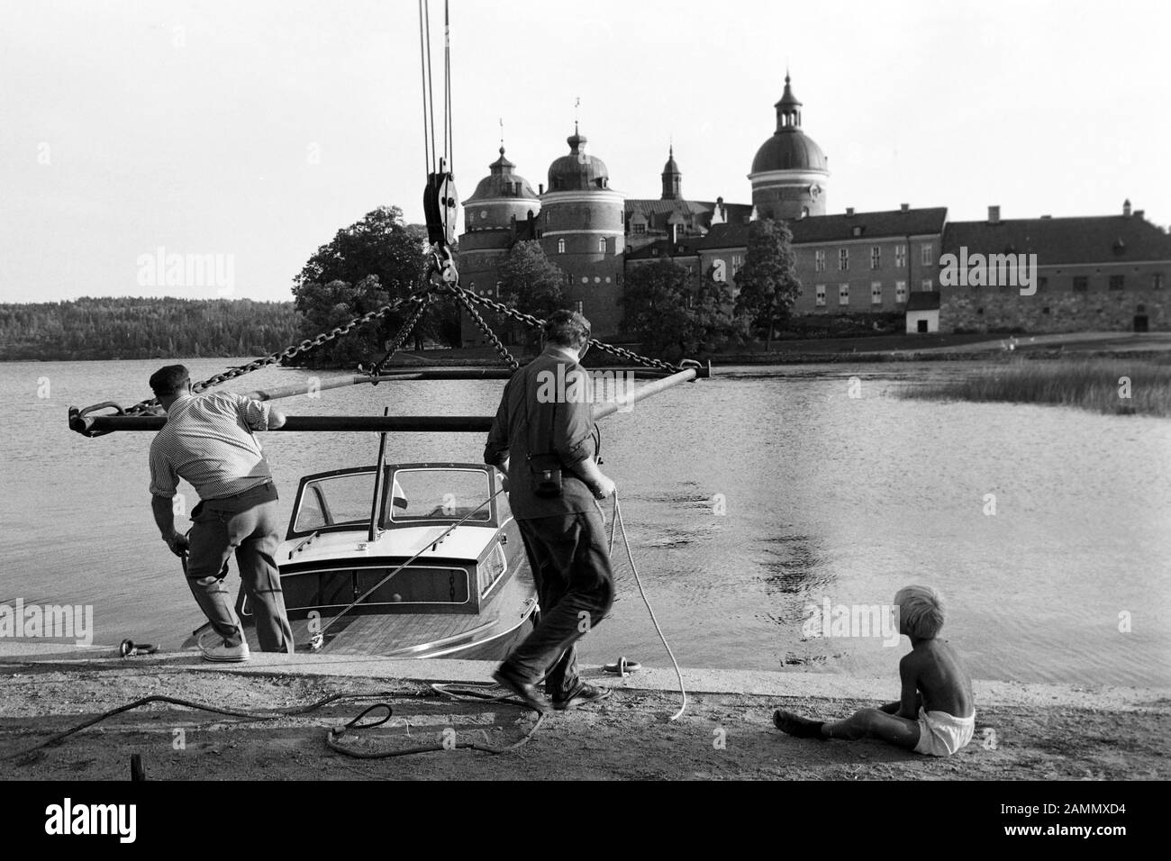 Seeblick auf Schloss Gripsholm am See Mälaren mit Boot und Männern (Tipo) am Anlegeplatz, bei Stockholm, Schweden, 1969. Vista lago del castello di Gripsholm sul lago di Mälaren con barca e uomini (bambini) all'ormeggio, vicino a Stoccolma, Svezia, 1969. Foto Stock