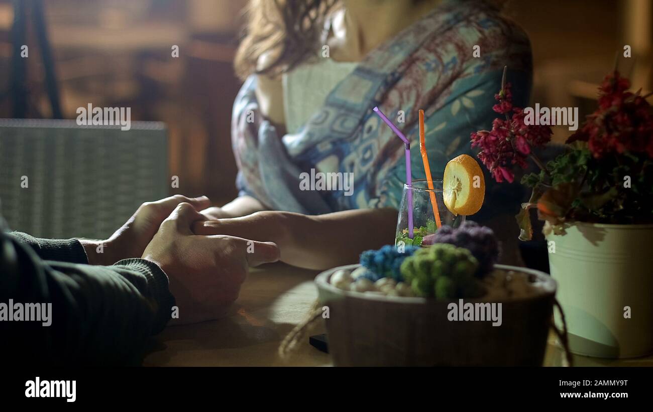 Coppia tenere le mani teneramente, mostrando sentimenti romantici in data, storia d'amore Foto Stock