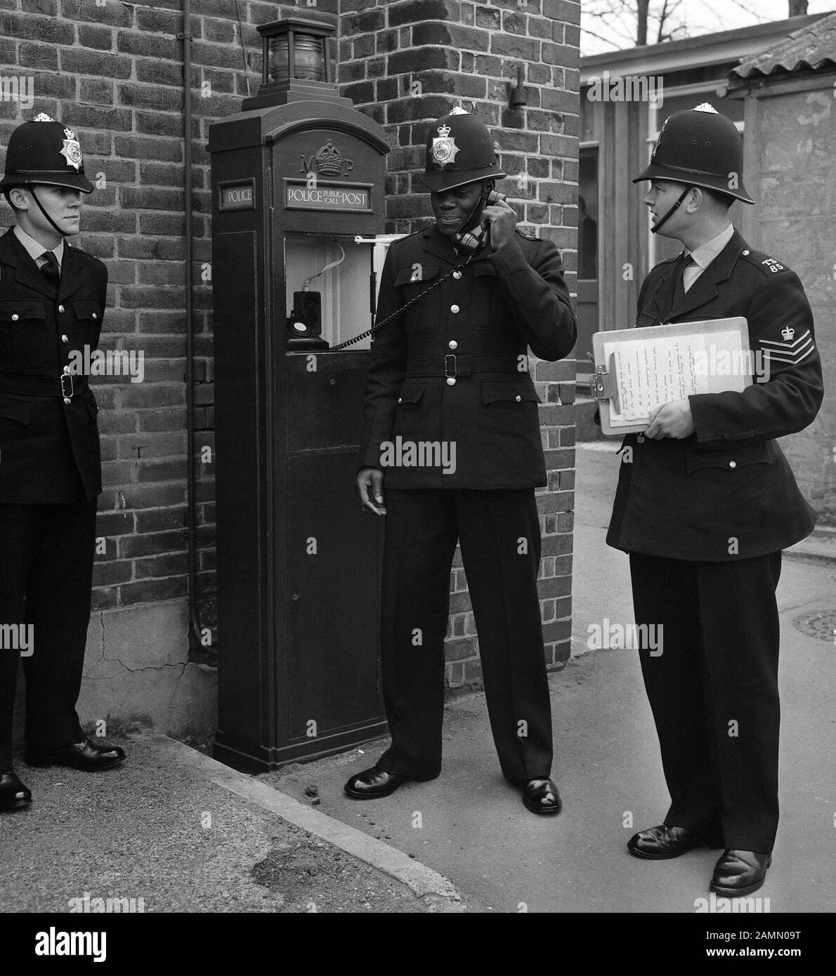 Sotto nove giorni di formazione come il primo poliziotto nero di Londra, PC Norwell Gumbs, 21, al Metropolitan Police Training College di Hendon, Londra, come la stazione Sgt John Aldridge gli indica di utilizzare un telefono di polizia. Foto Stock