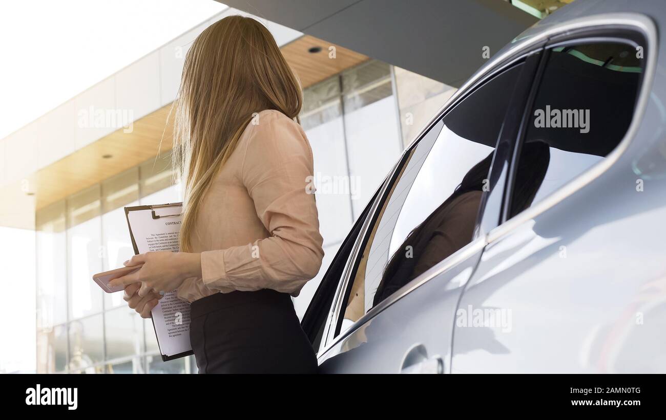 Elegante lady broker in contratto, in attesa di cliente, in piedi vicino auto Foto Stock