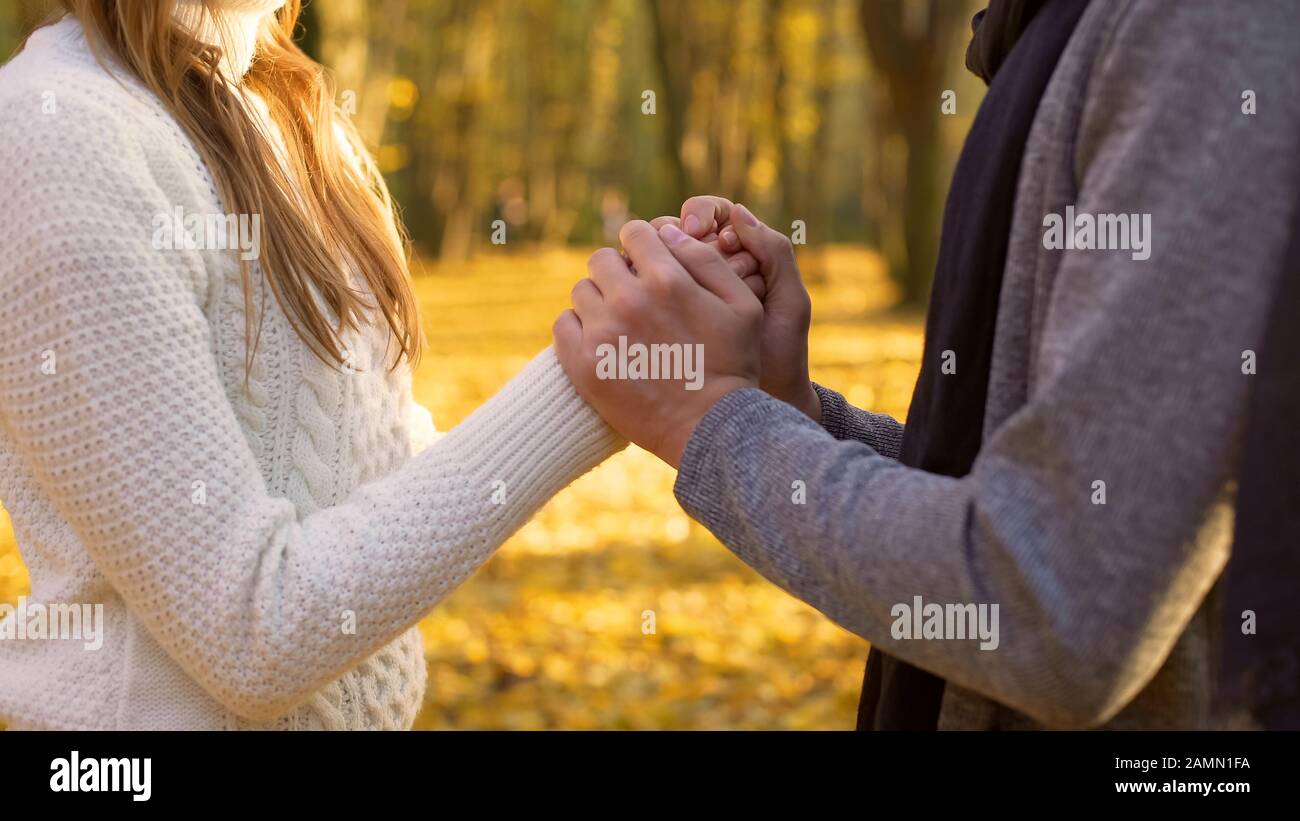 Ragazzo che riscalda le mani delle sue fidanzate, atmosfera romantica, data in autunno boschi Foto Stock