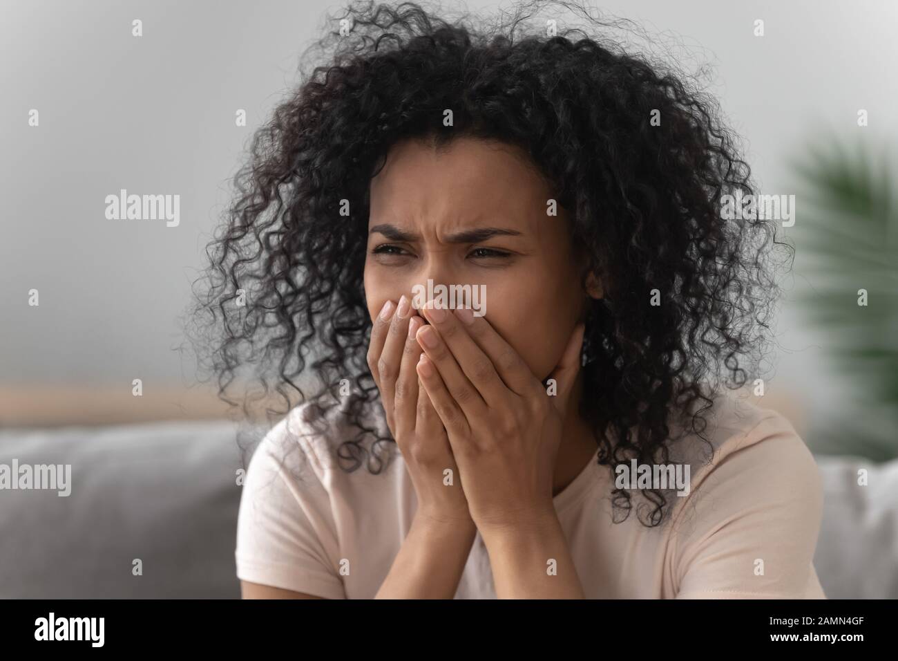 Donna africana addolorata che piange seduto sul divano Foto Stock