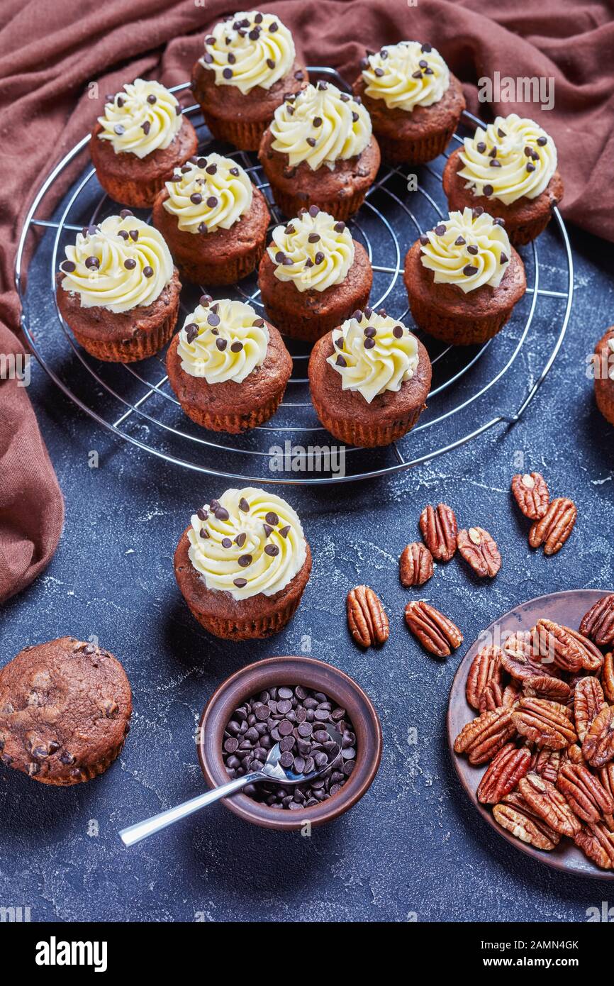 Cupcake al cioccolato pecan sormontato da una glassa di crema di buttercream su una griglia metallica su un tavolo di cemento, vista verticale dall'alto Foto Stock