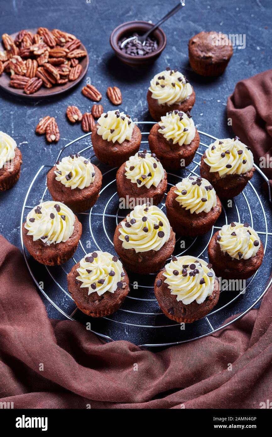 Cupcake al cioccolato pecan sormontato da una glassa di crema di buttercream su una griglia metallica su un tavolo di cemento, vista verticale dall'alto Foto Stock