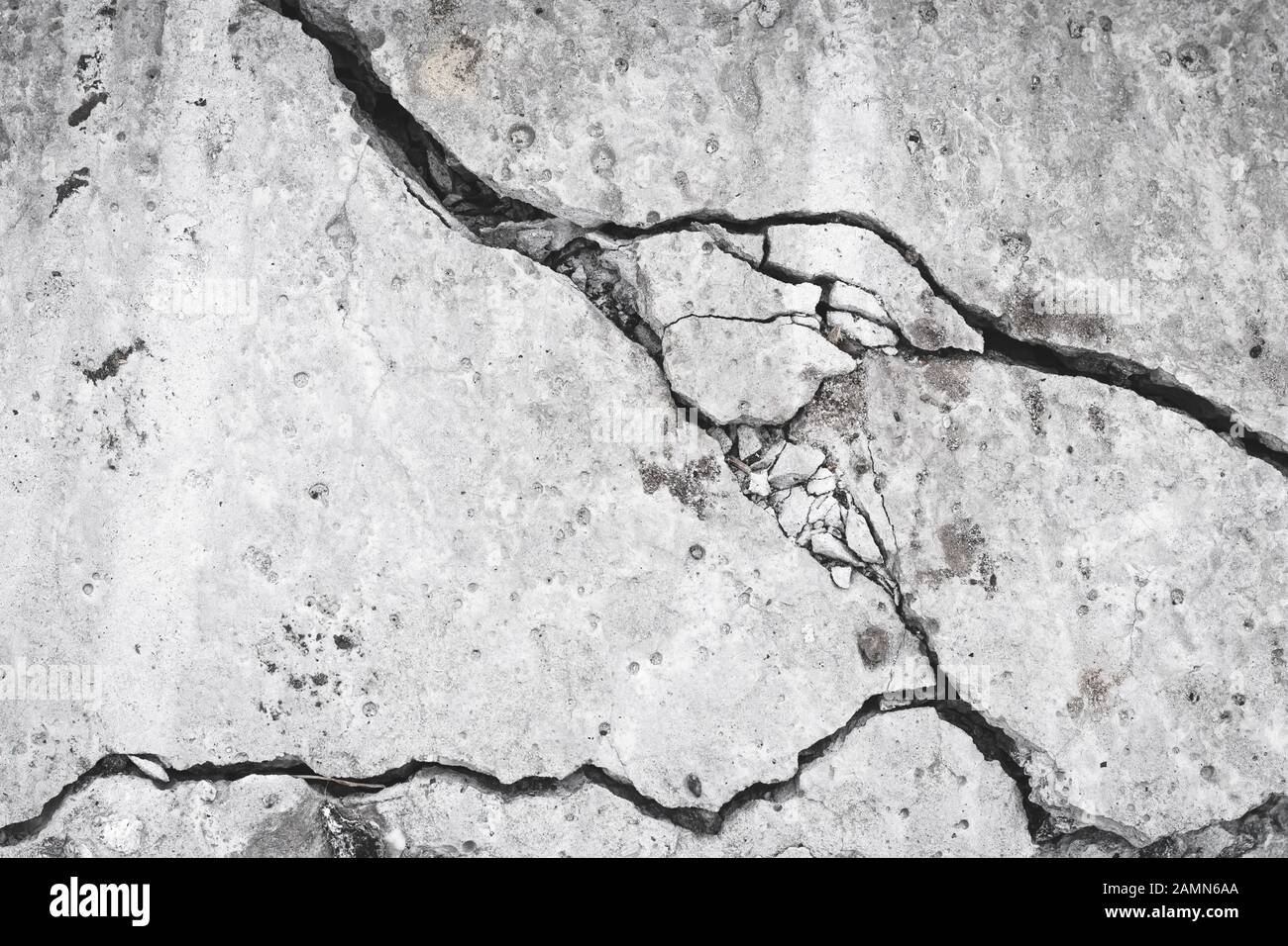 Rovinato muro di cemento, crepe e buco nella lastra di cemento. Grunge superficie, concetto di pericolo. Effetto danno, texture. Sfondo grigio pietra, materiale Foto Stock