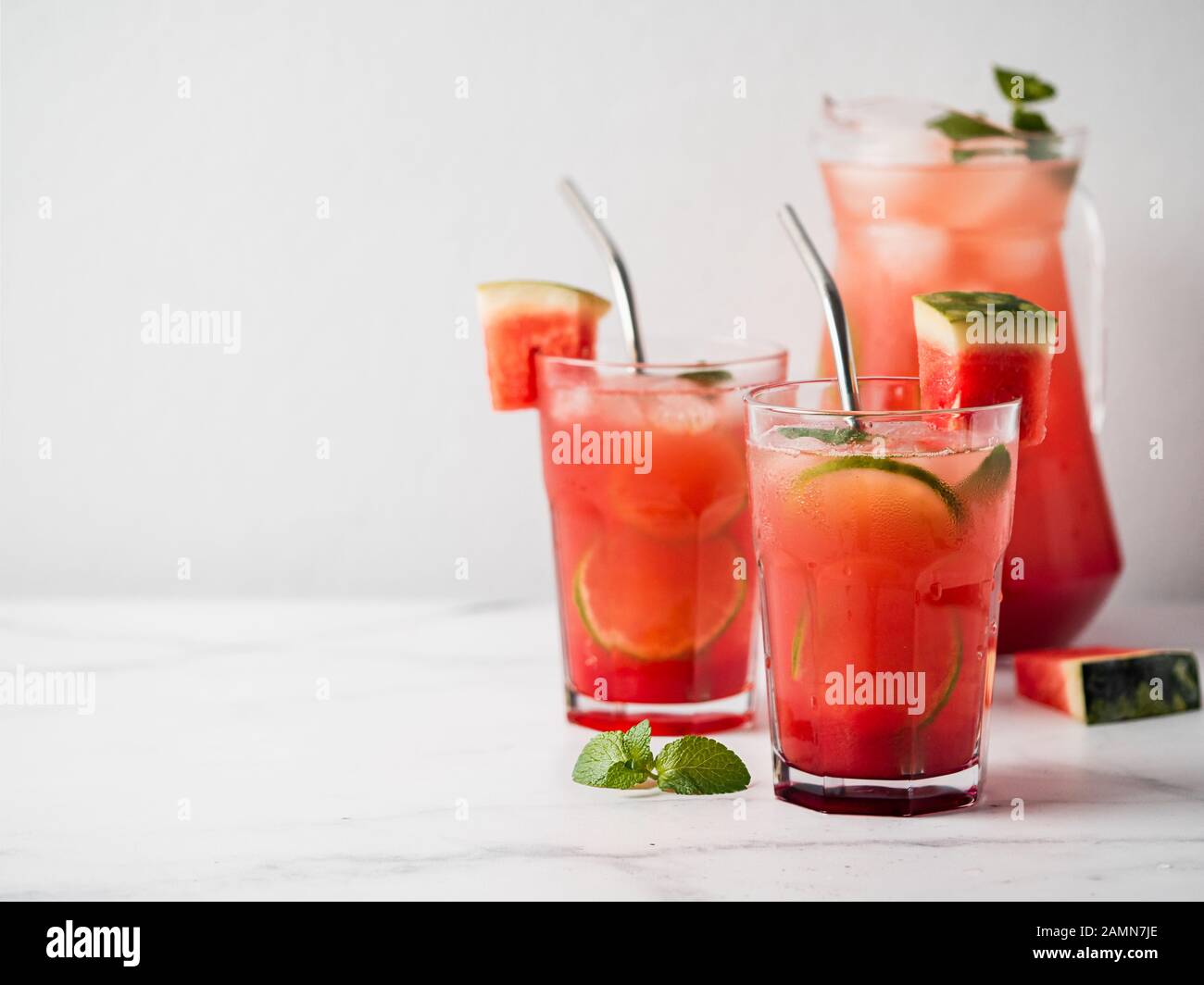 Raffreddamento ad anguria con calce, menta e ghiaccio. Perfetta bevanda a base di anguria fatta in casa in bicchieri con cannucce di metallo su sfondo bianco, copiare lo spazio lasciato per il testo Foto Stock