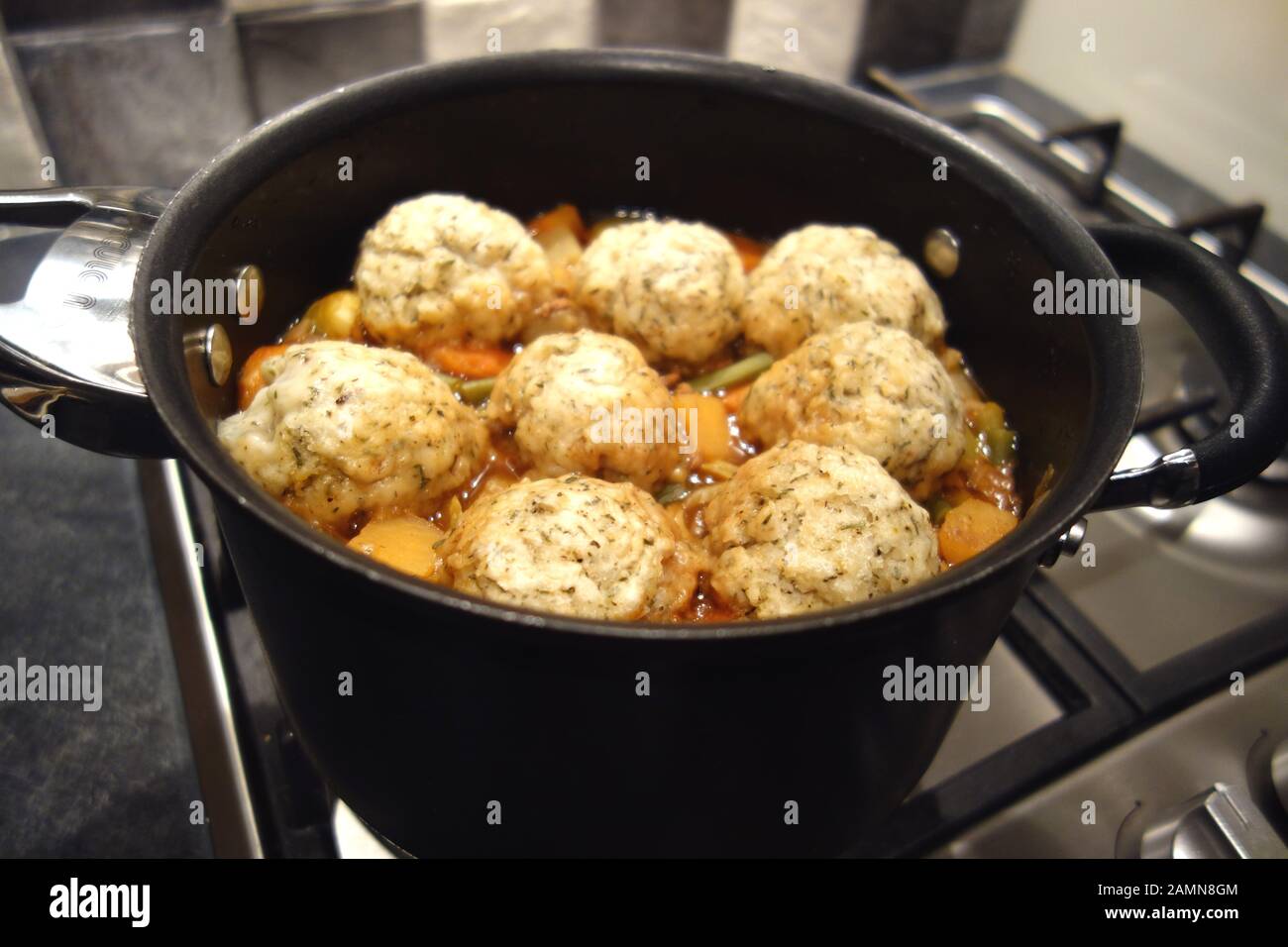 Grande Nero Pan casereccio Brodo vegetale & Otto Herby gnocchi cottura su un piano cottura a gas. Foto Stock