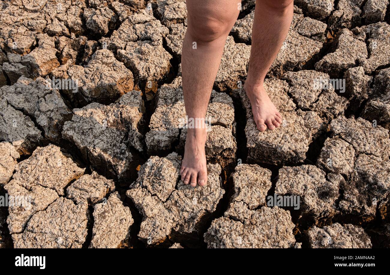 Le donne che si trovano su terreni crackizzati e secchi in aree aride paesaggio, Siccità crisi Concetto Foto Stock