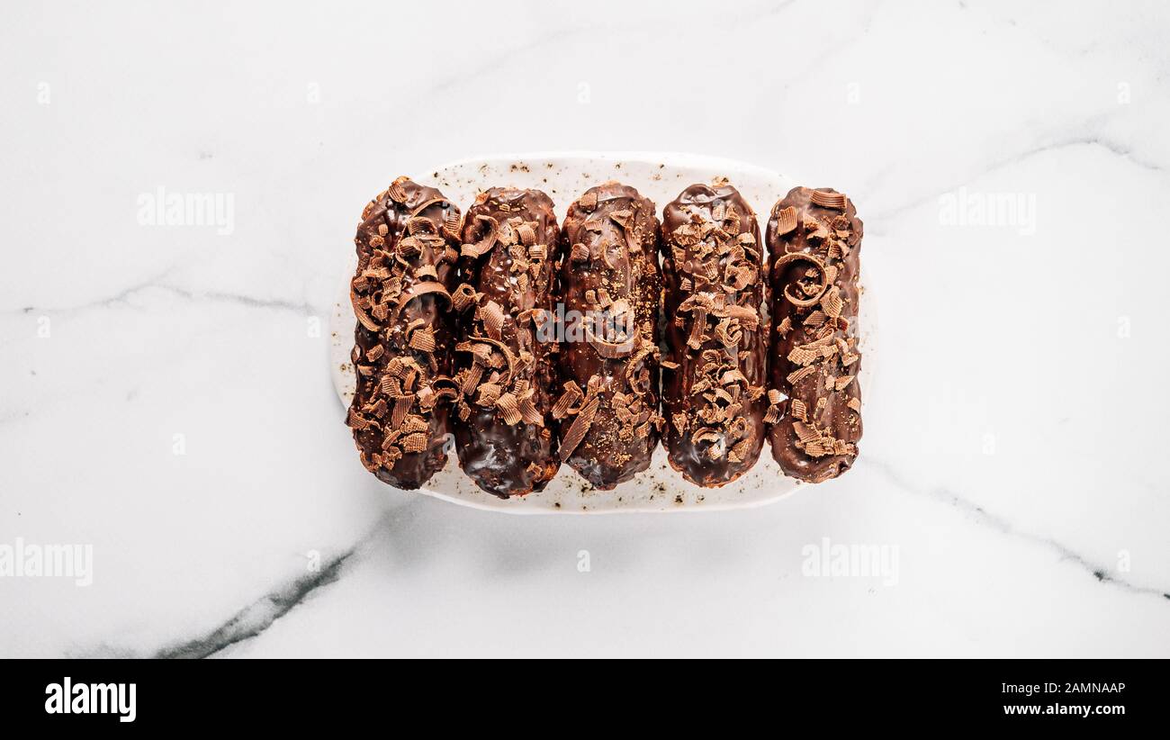 Set di airs fatti in casa con cioccolato su sfondo di marmo. Vista dall'alto di deliziosi e salutari profittatori con glassa al cioccolato. Copiare lo spazio per il testo o il disegno. Banner Foto Stock