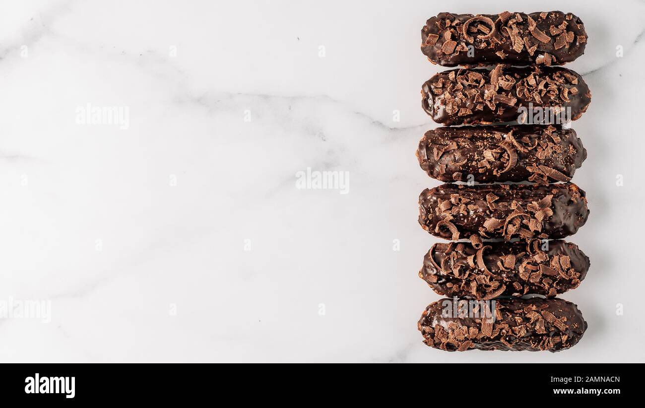 Set di airs fatti in casa con cioccolato su sfondo di marmo. Vista dall'alto di deliziosi e salutari profittatori con glassa al cioccolato. Copiare lo spazio per il testo o il disegno. Banner Foto Stock