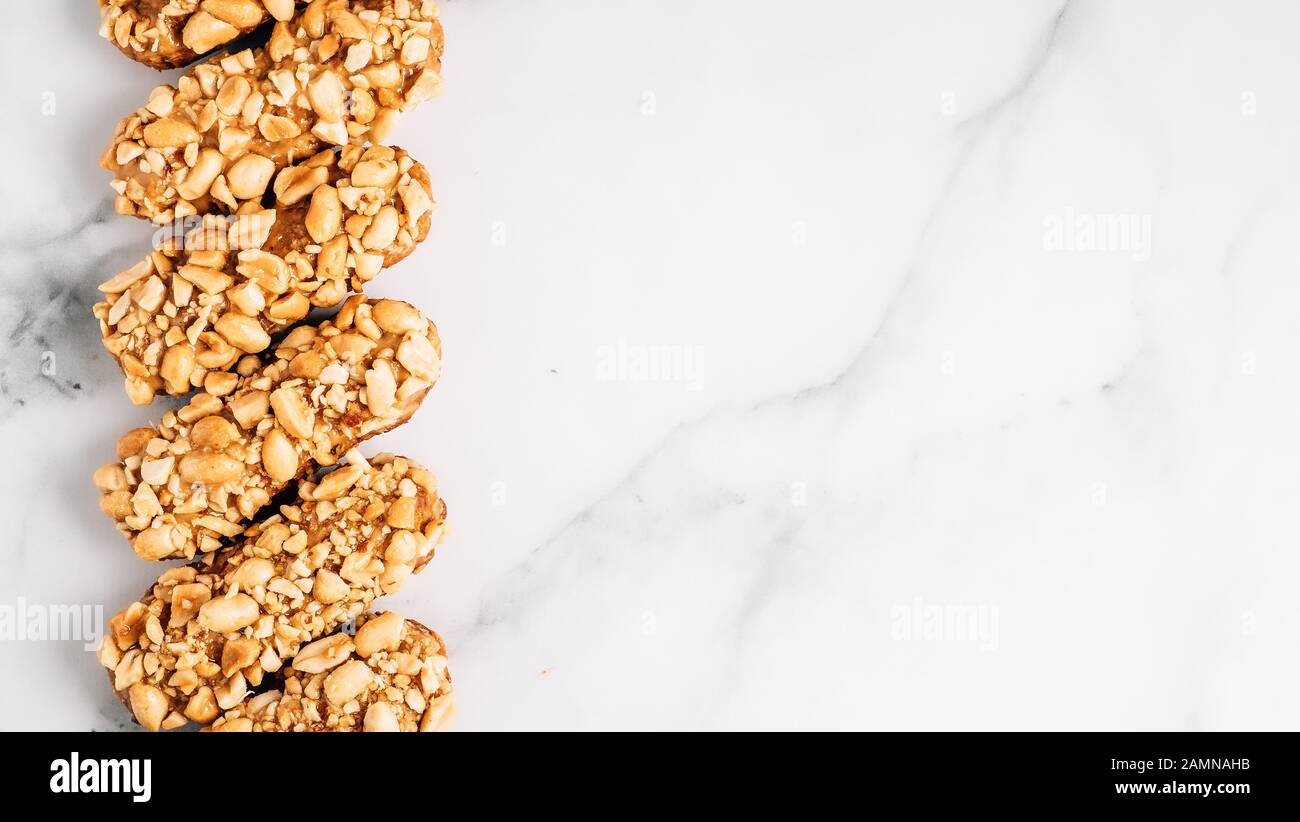 Set di eclairs fatti in casa con decorazioni di arachidi su sfondo marmo. Vista superiore della deliziosa profitroles sano con i dadi. Copia spazio per il testo o il design. Foto Stock
