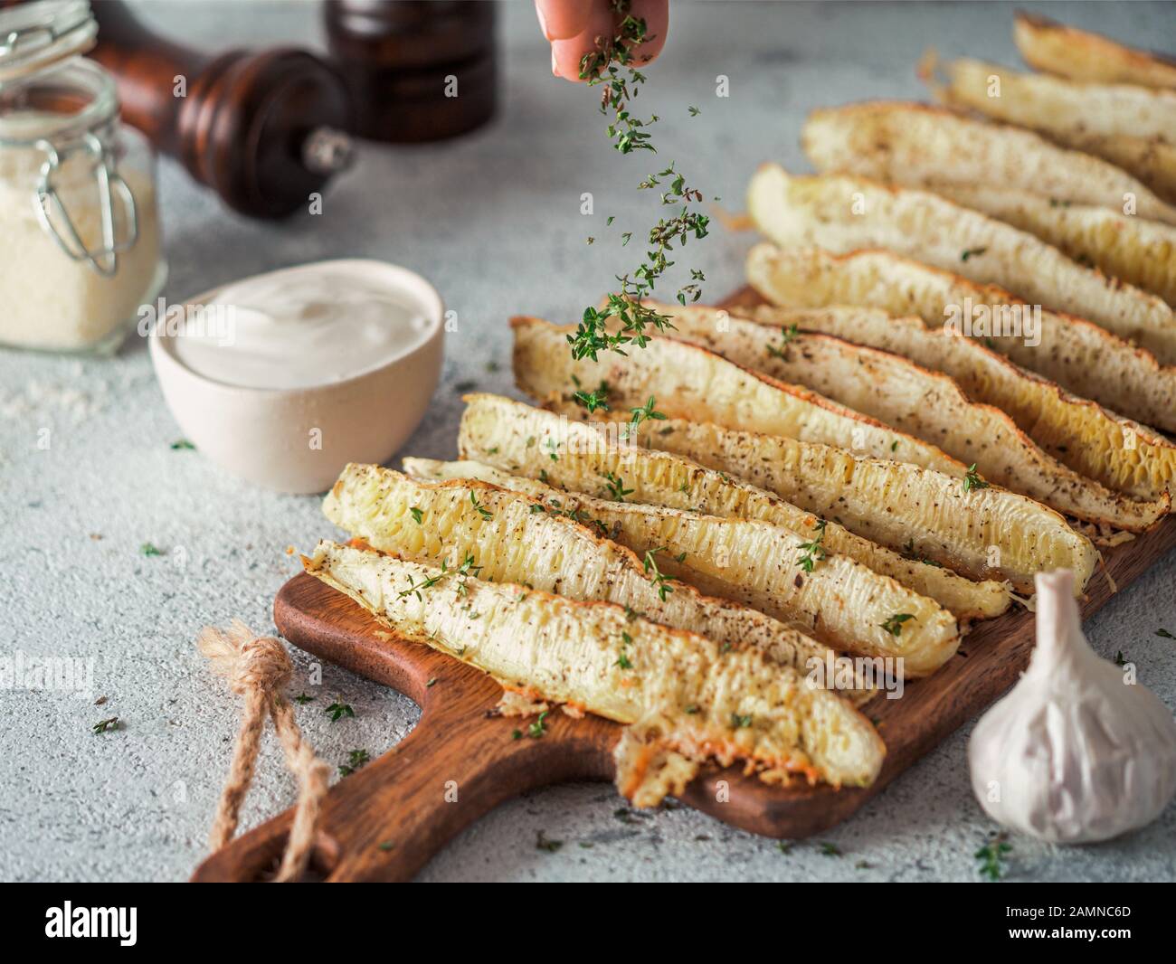 Zucchine Aglio Al Parmigiano Al Forno. Le foglie di timo cadono su zucchine cotte al forno. Idee e ricette per un pranzo o una cena facile e salutare Foto Stock