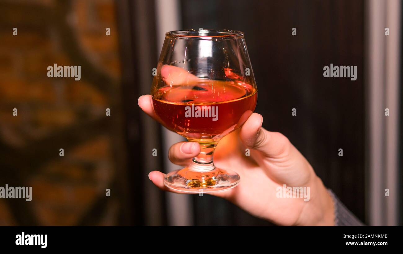 Primo piano di persone che tengono un bicchiere con whisky o bourbon. Concetto di vita notturna Foto Stock