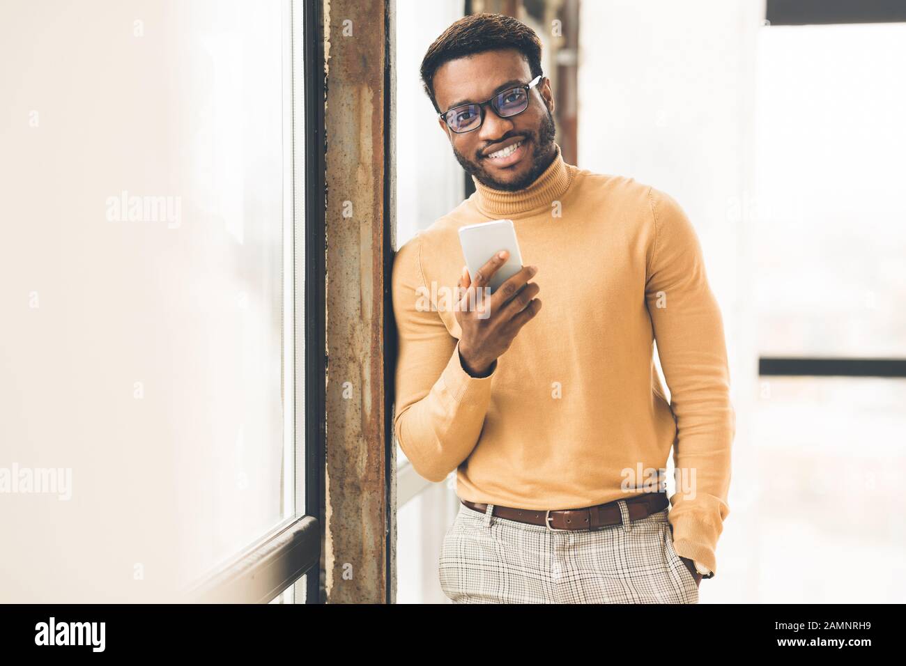 Uomo afro di successo in piedi vicino alla finestra in ufficio Foto Stock