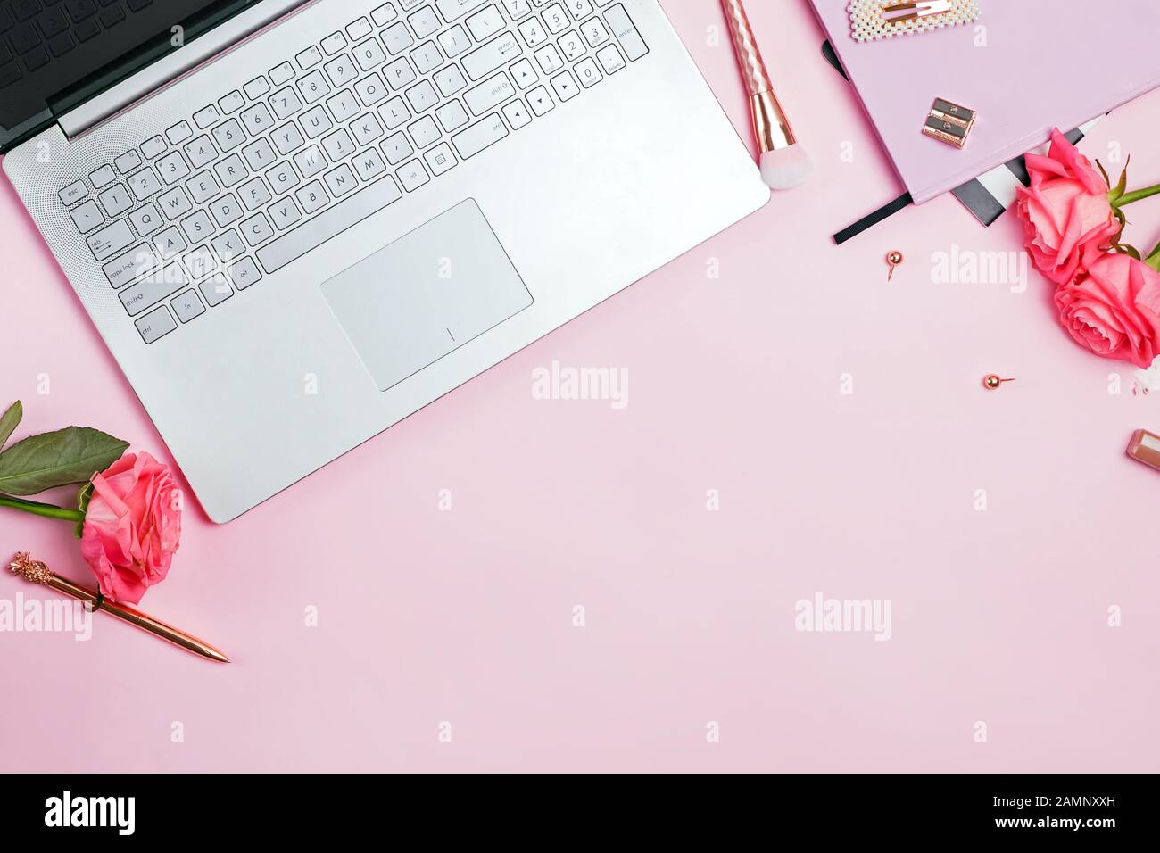 Scrivania femminile concetto di area di lavoro. Vista superiore del portatile, colore oro cancelleria e rose rosa sul tavolo. Foto Stock