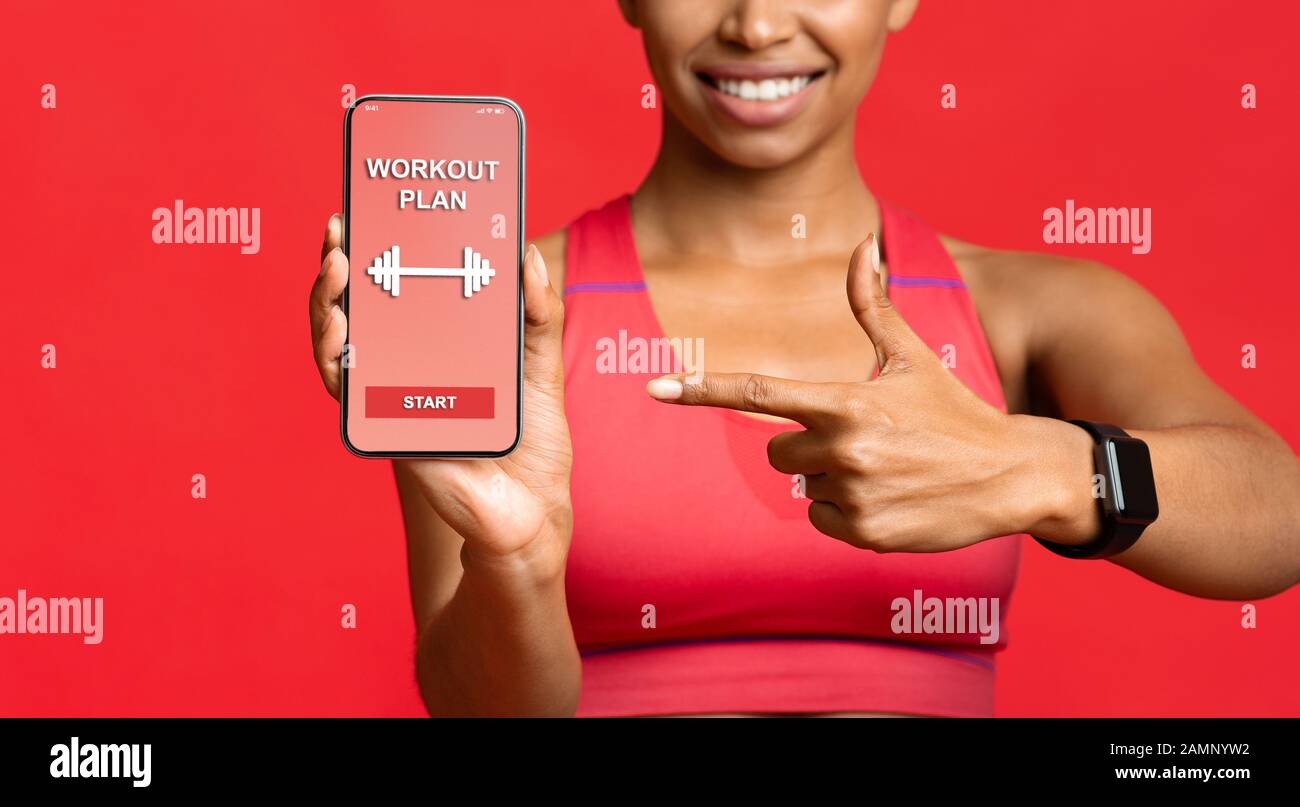 Signora fitness che punta all'applicazione di allenamento sullo schermo del telefono Foto Stock