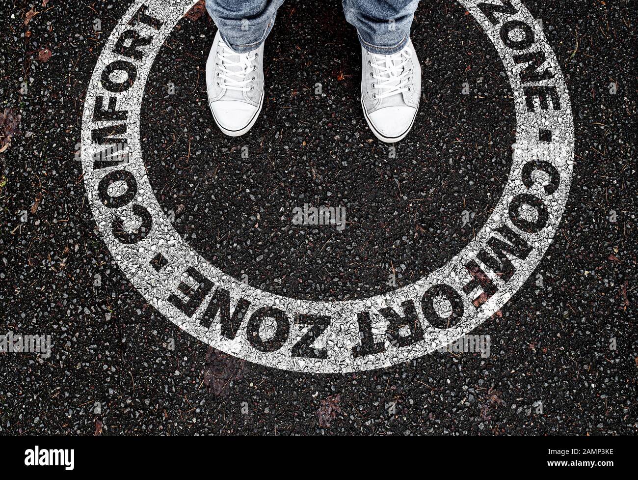 Gambe di persone in piedi in contrassegno circolare su strada con testo ZONA COMFORT, essere in o lasciare il proprio concetto di zona comfort Foto Stock