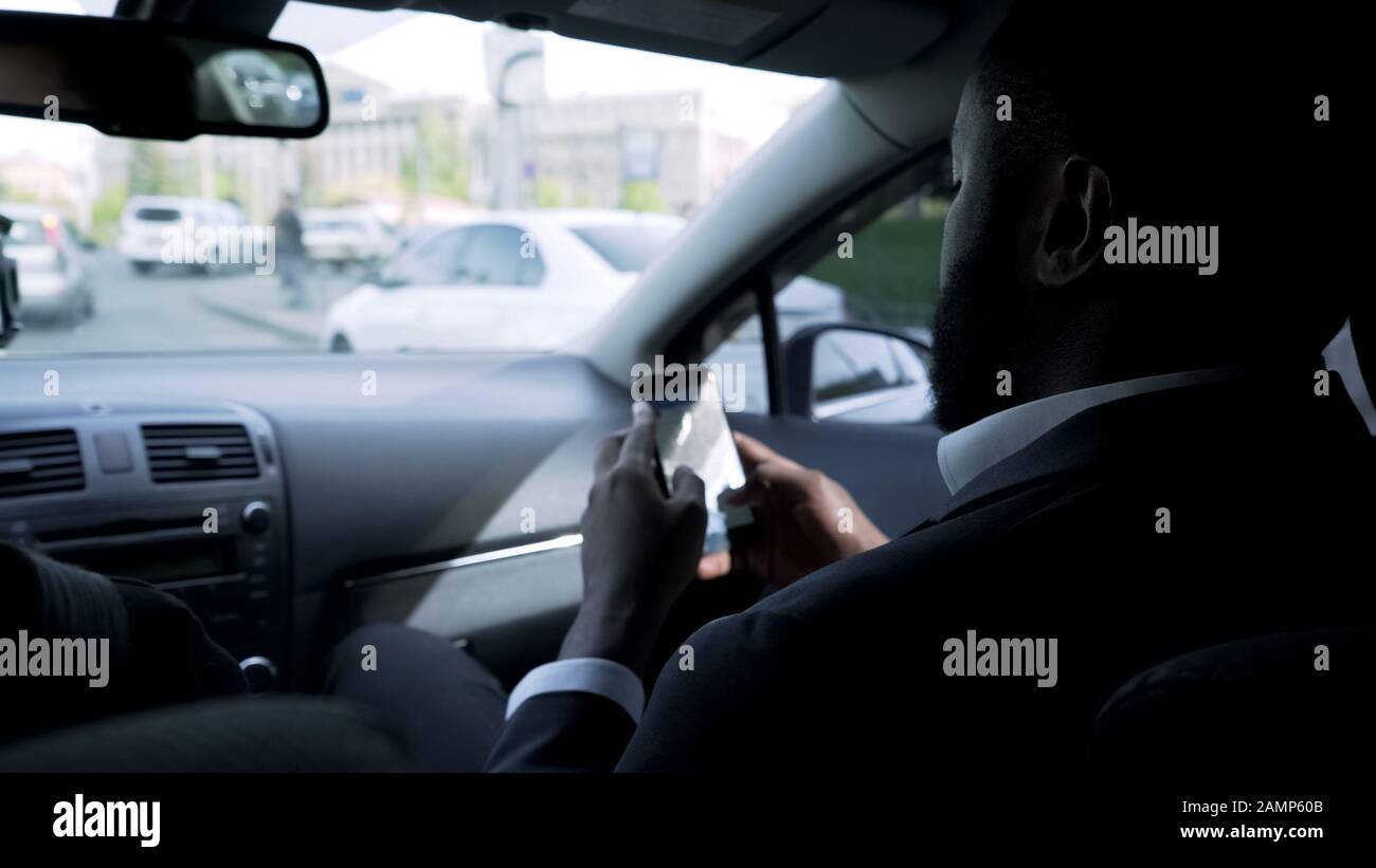 L'uomo d'affari afro-americano sta andando incontrare, guardando attraverso le domande sul telefono Foto Stock