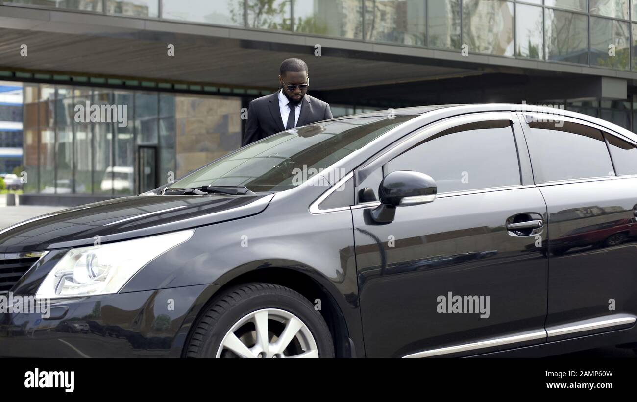 Il conducente personale apre la porta del passeggero, portando il capo al business center Foto Stock