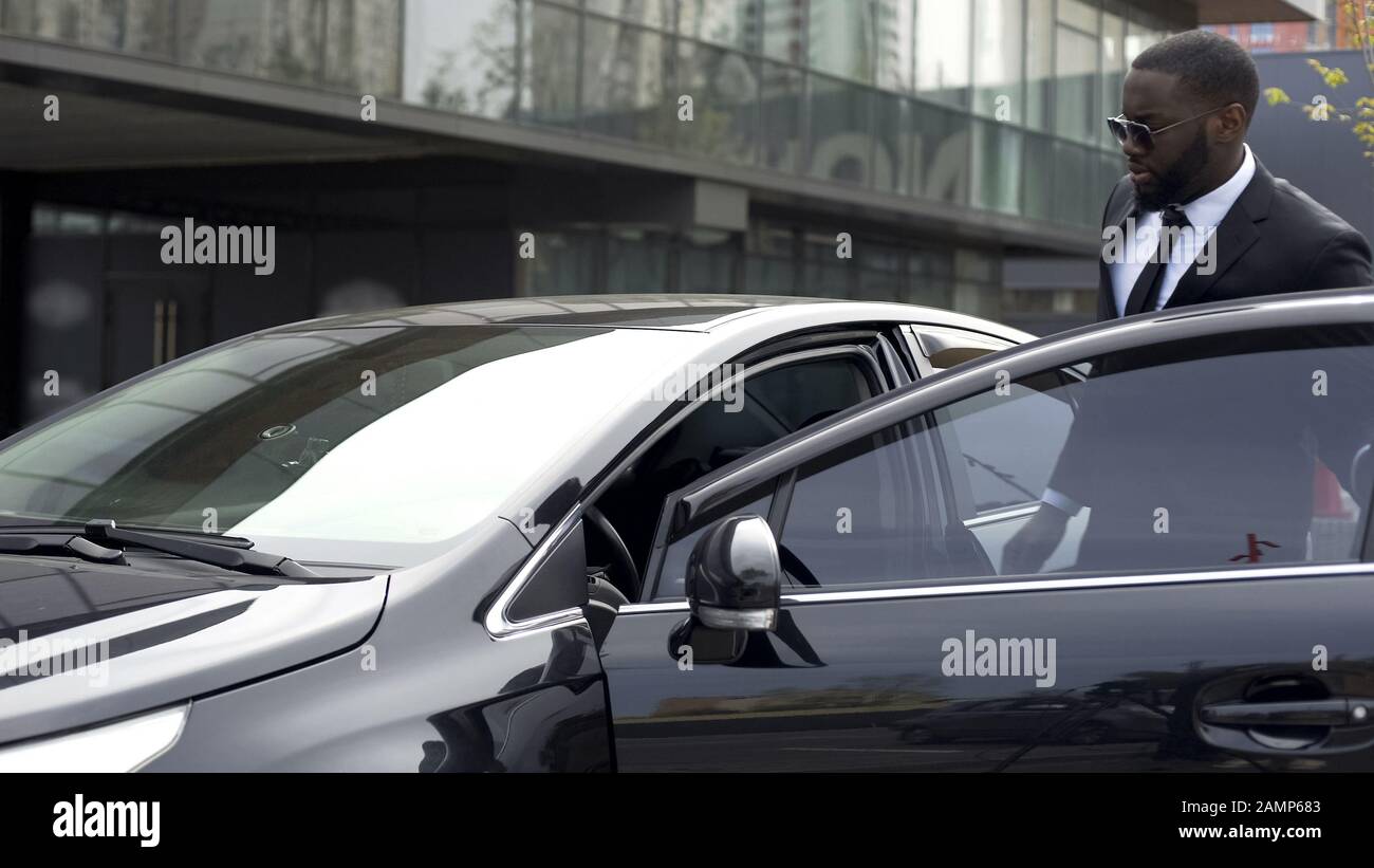 Bell'uomo afro-americano seduto nella sua nuovissima auto, lasciando lo showroom Foto Stock