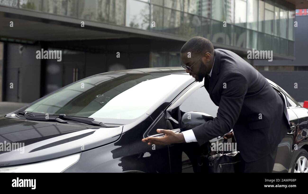 Uomo pedante e scrupoloso che nota la polvere sulla sua auto e che entra in collera Foto Stock