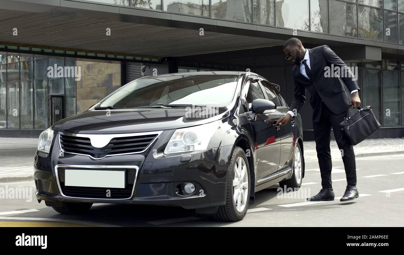 Ricco africano americano uomo porta di apertura di auto di lusso con chiave speciale, sicurezza Foto Stock