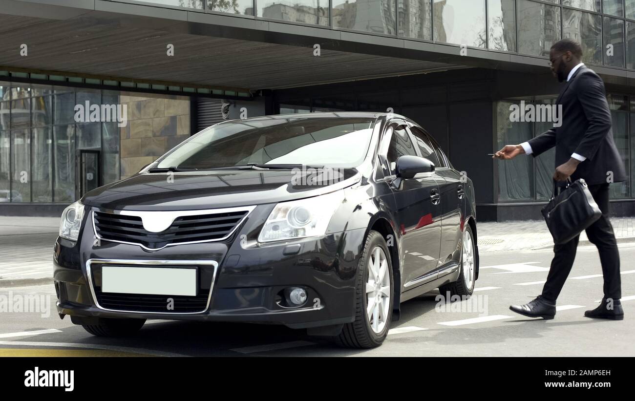 L'uomo d'affari spegne il sistema di allarme dell'automobile prima di entrare e guidare a casa Foto Stock