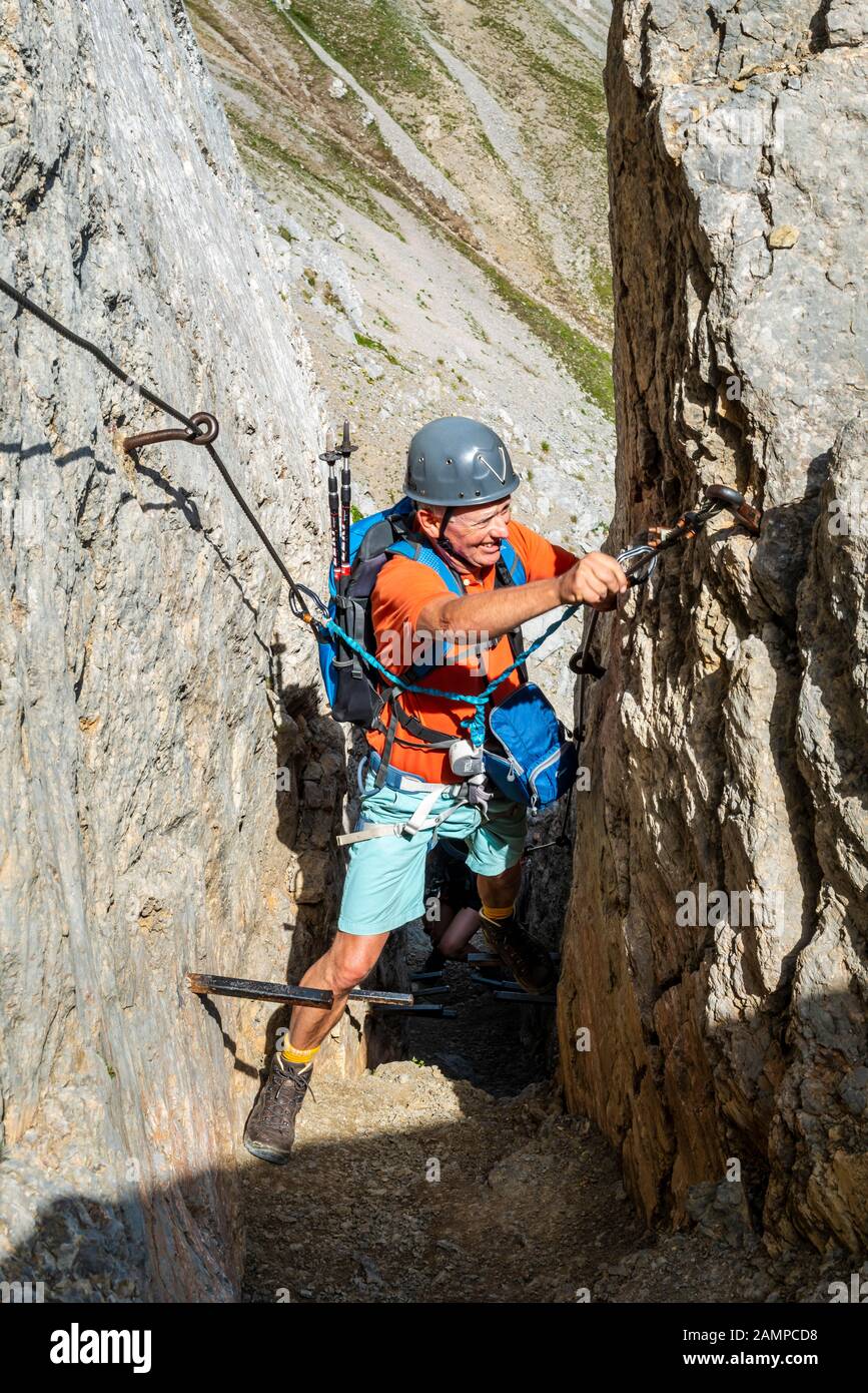 Alpinista, uomo con casco da arrampicata su una corda fissa sicura, Mittenwald via ferrata, Monti Karwendel, Mittenwald, Germania Foto Stock