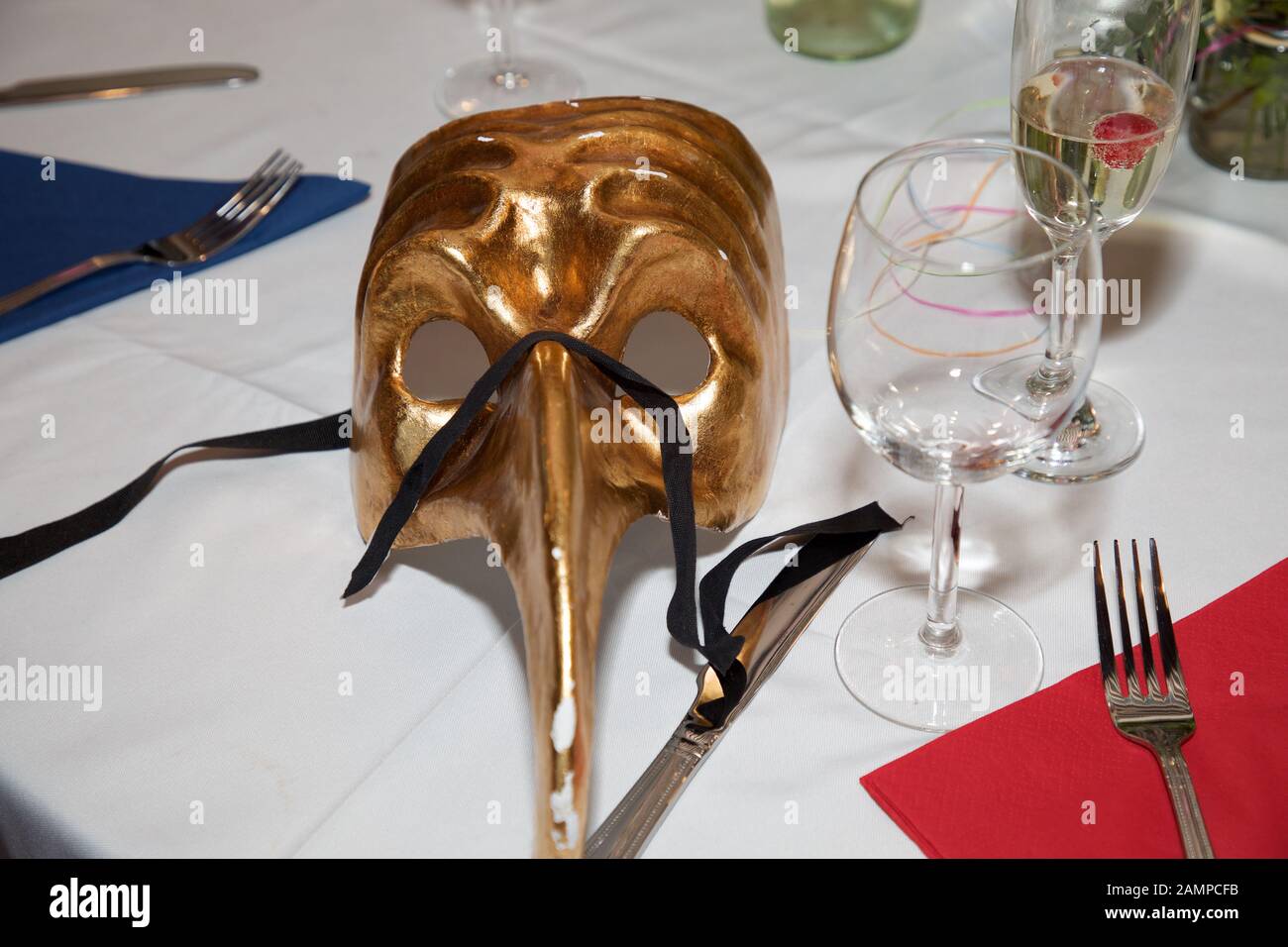 Una maschera da palla in maschera dorata su un tavolo da pranzo. Carnevale maschera dell'occhio carnevale, accessorio di abito da festa, ballo del costume del partito di Carnevale. Foto Stock