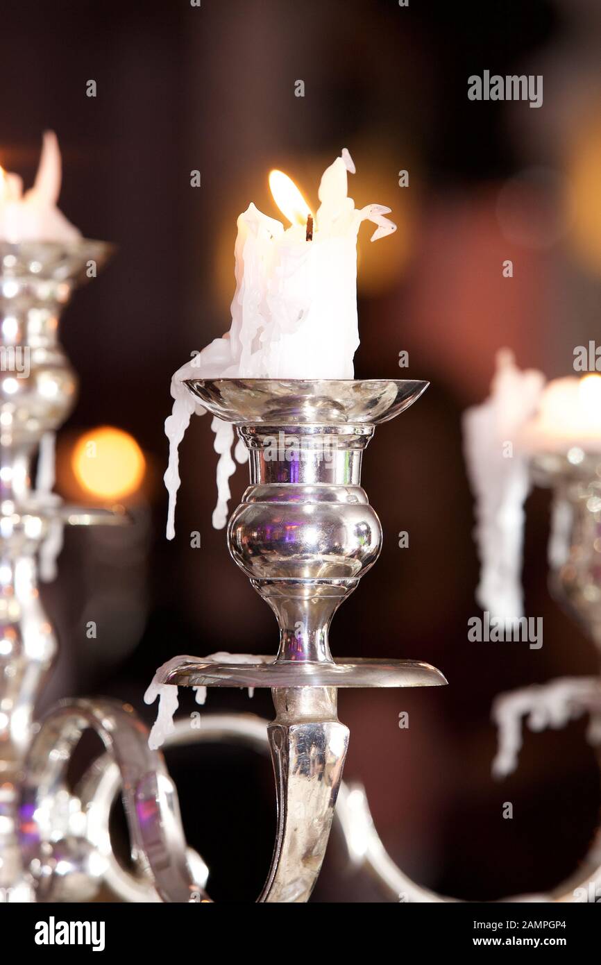 Candele bruciate in eleganti portacandele color argento. Foto Stock