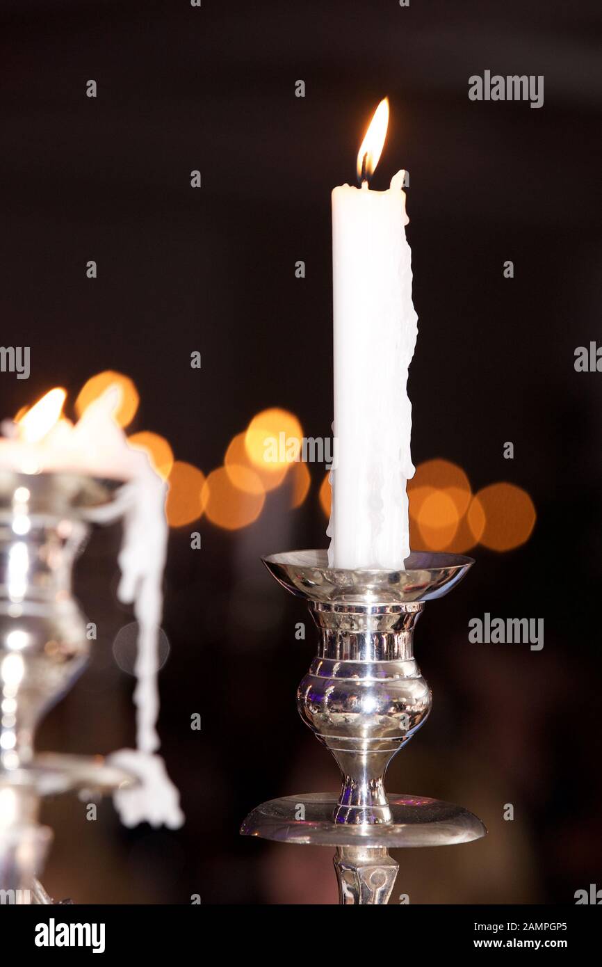 Candele bruciate in eleganti portacandele color argento. Foto Stock