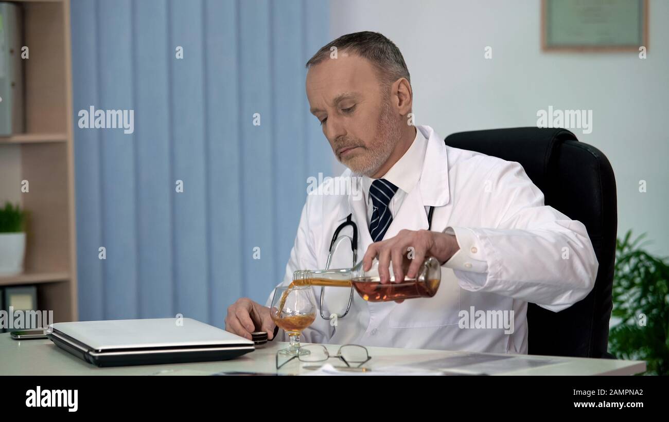 Stanco medico bere alcol dopo una dura giornata di lavoro, lavoro stressante, relax Foto Stock