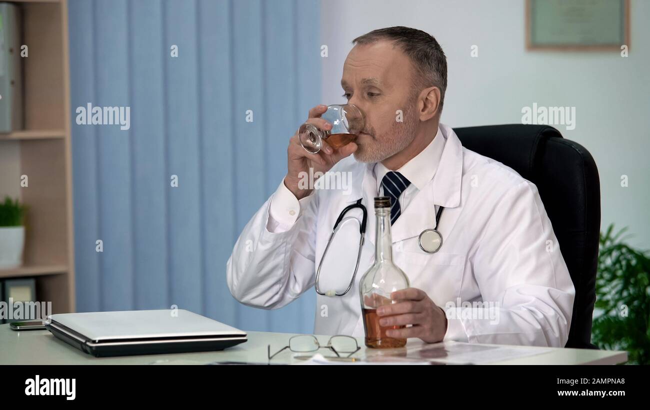 Irresponsabile medico bere alcol per rilassarsi sul lavoro, occupazione stressante Foto Stock