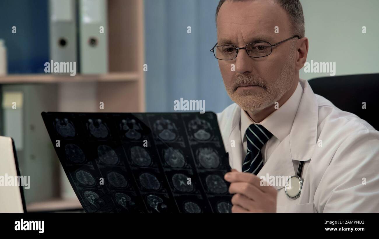 Neurologo che controlla l'immagine MRI, conferma la patologia nella corteccia cerebrale dei pazienti Foto Stock