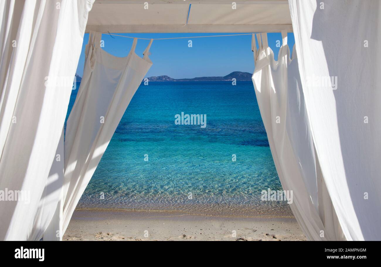 Mare blu e spiaggia della Sardegna vista attraverso le tende bianche di  sdraio Foto stock - Alamy
