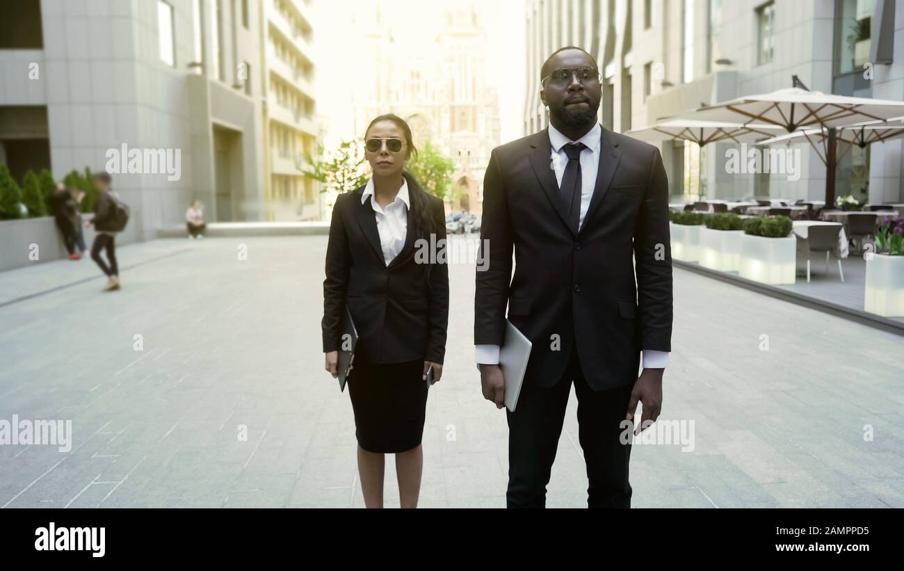 Agenti federali maschili e femminili che camminano con mandato di arresto sospetto, sicurezza Foto Stock