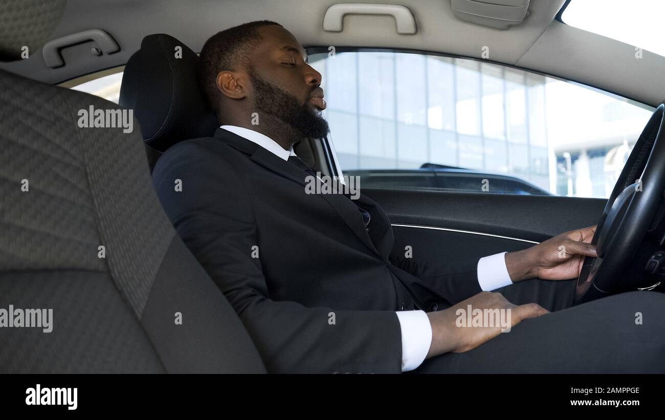 Imprenditore afroamericano sovraccarico seduto in auto, stanco dopo una giornata stressante Foto Stock
