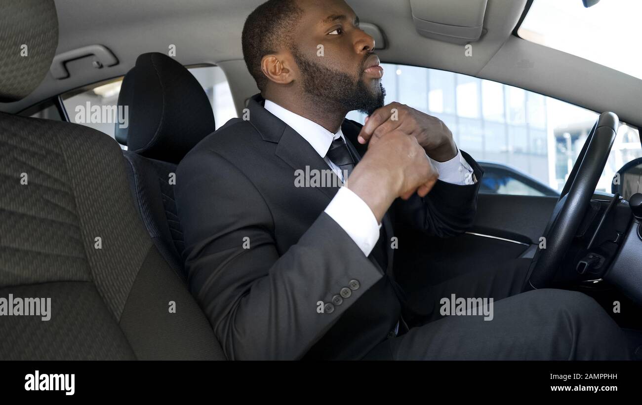 Bell'uomo nero in abito da lavoro che guarda in specchio per auto, pronto per la data Foto Stock