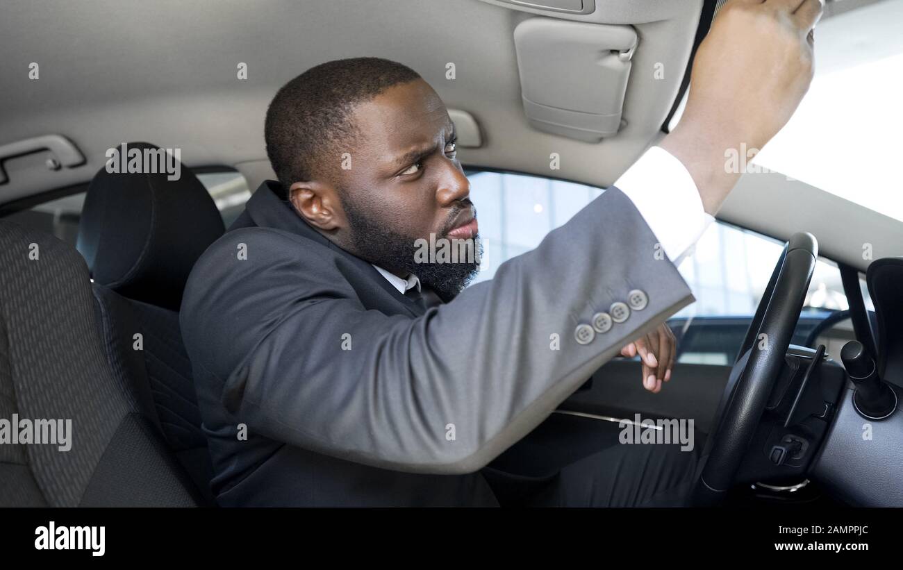 Un uomo d'affari sospetto che guarda nello specchietto retrovisore, nota la ricerca spia su strada Foto Stock