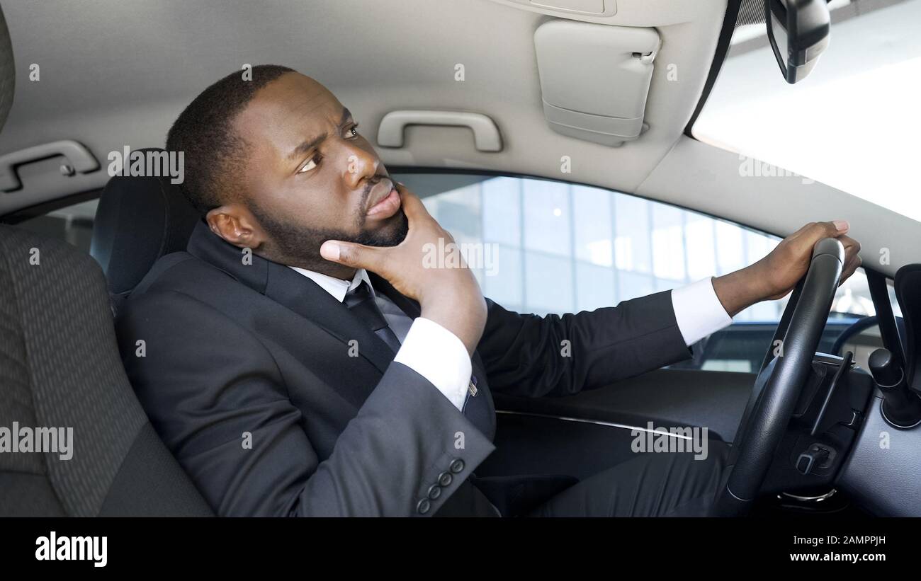 Bell'uomo d'affari afro-americano che guarda in auto specchio, avendo dubbi Foto Stock