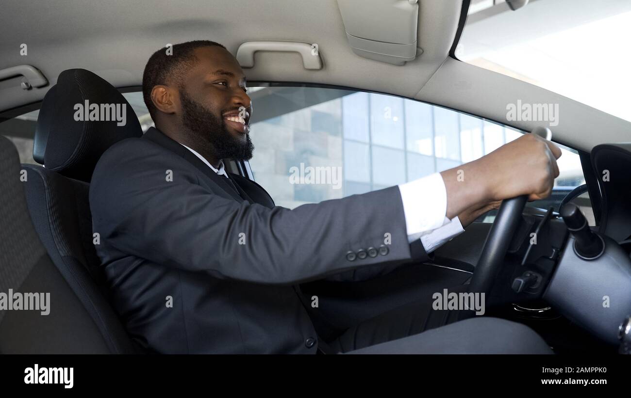 Uomo soddisfatto in abito da lavoro seduto in auto, acquisto di successo, felicità Foto Stock