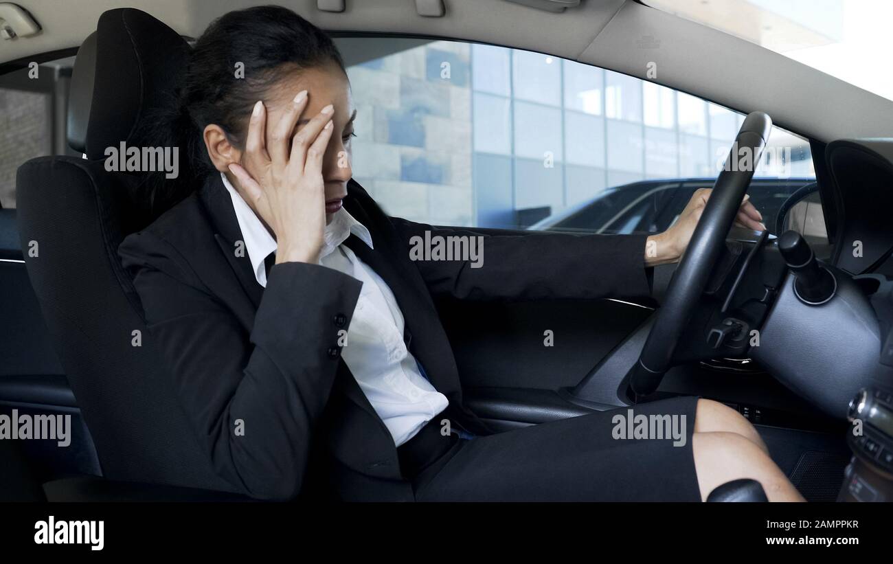Donna d'affari in tuta seduta in auto, sensazione di malessere e stanchezza, sintomi pms Foto Stock