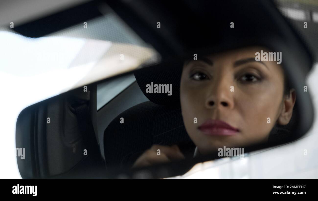 Bella lady reflection in posteriore-view specchio di auto, sospetto ombroso concessionario Foto Stock
